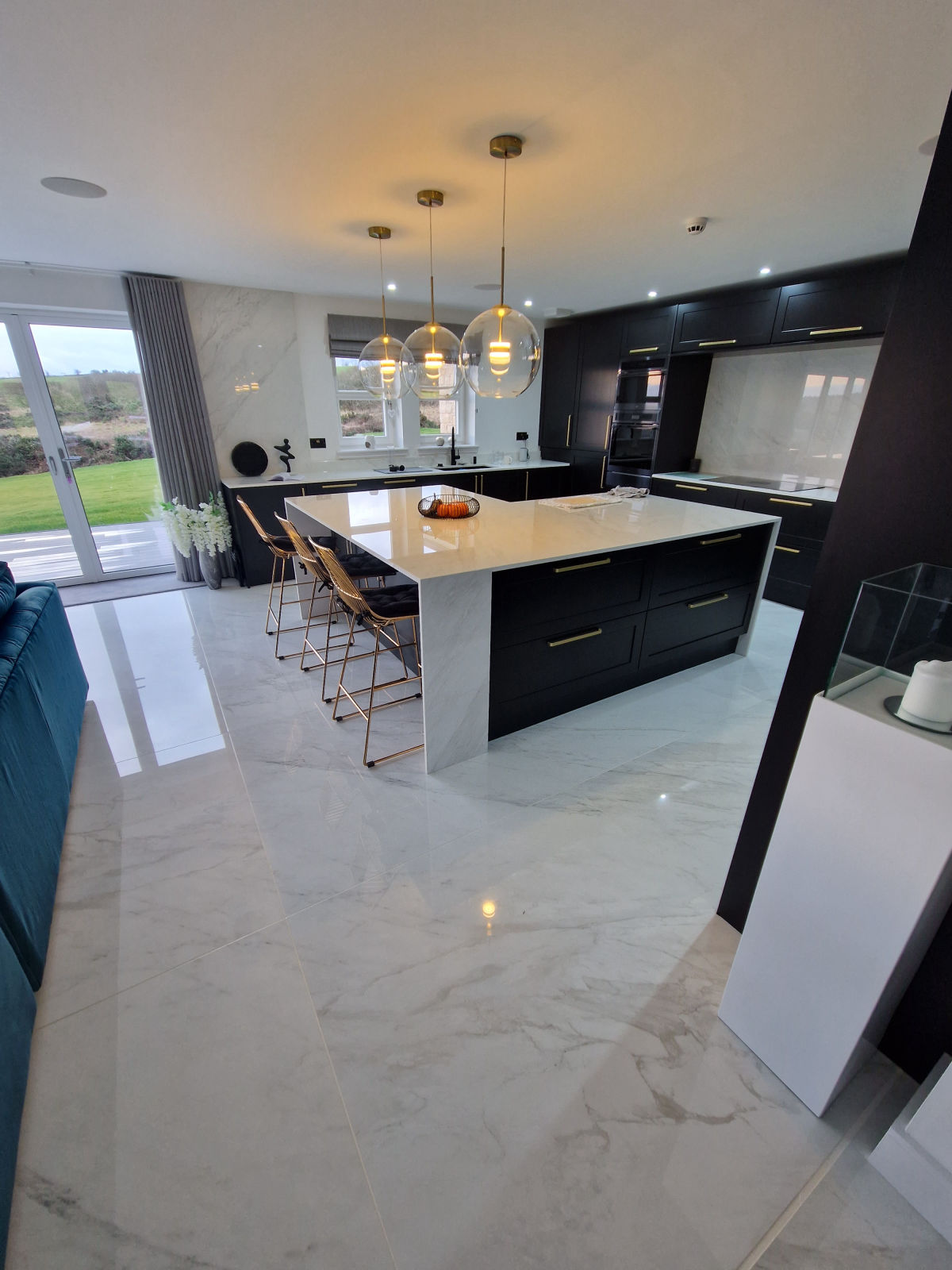 A polished marble-effect floor through an open-plan kitchen with a quartz island