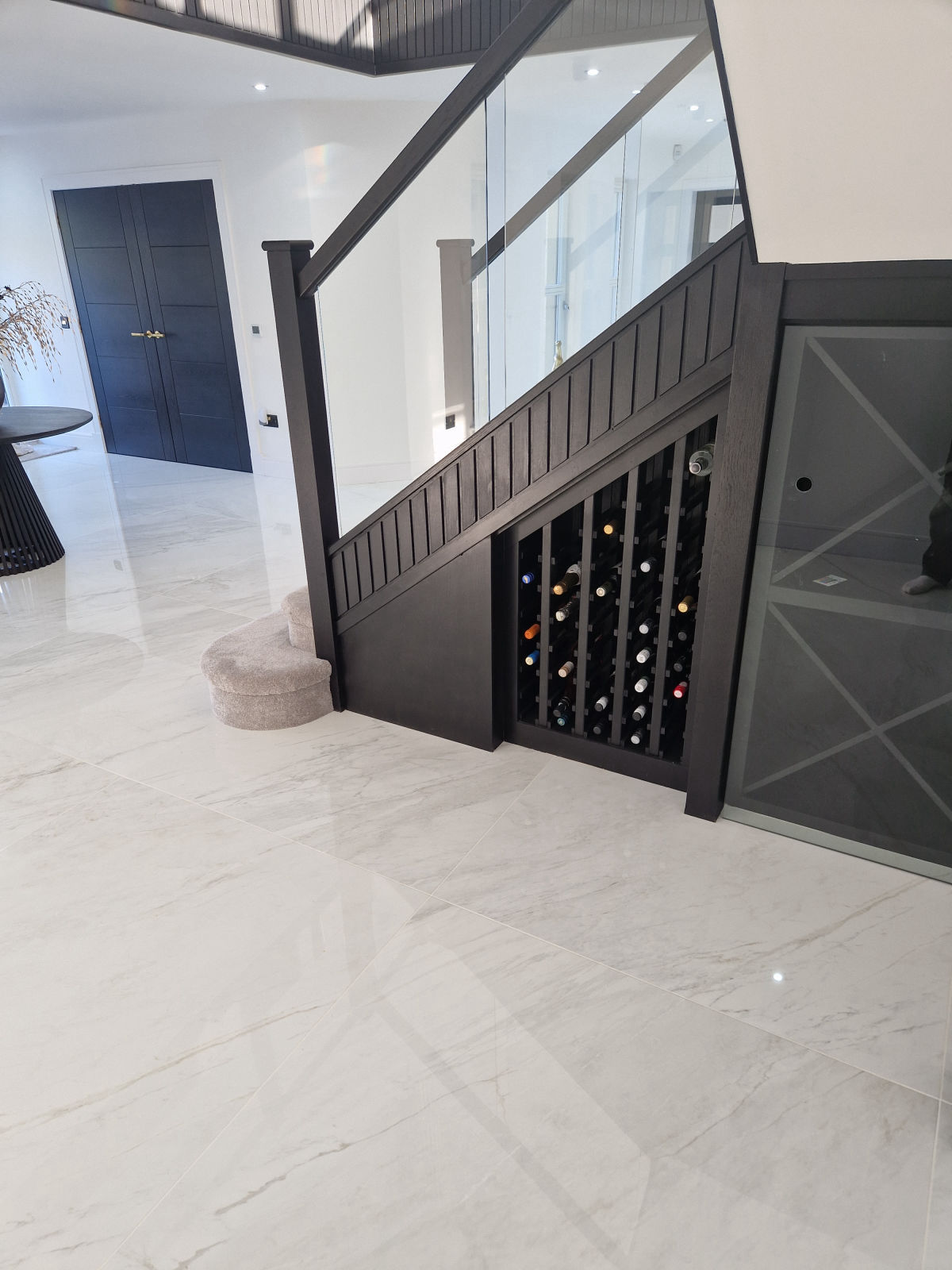 Large-format marble-effect floor tiling set out around the foot of a staircase